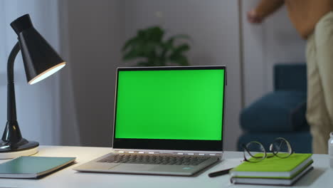 Mann-Schaltet-Stehlampe-In-Wohnung-Aus-Und-Schließt-Laptop-Mit-Chroma-Key-Display-Auf-Tisch-Im-Zimmer-Home-Office-Des-Freiberuflers-Am-Ende-Des-Arbeitstages